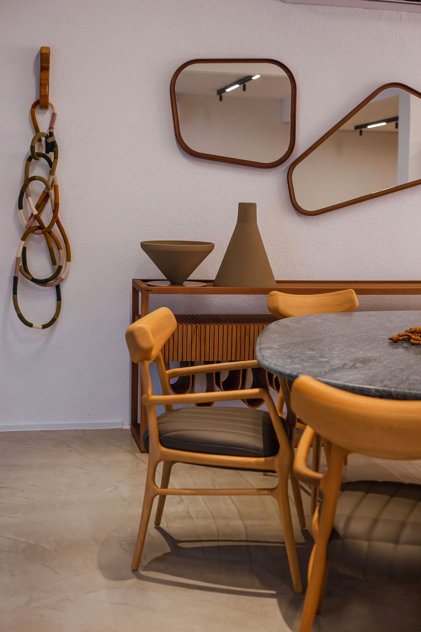 Sala de jantar com mesa de pedra, cadeiras de madeira maciça e aparador ripado