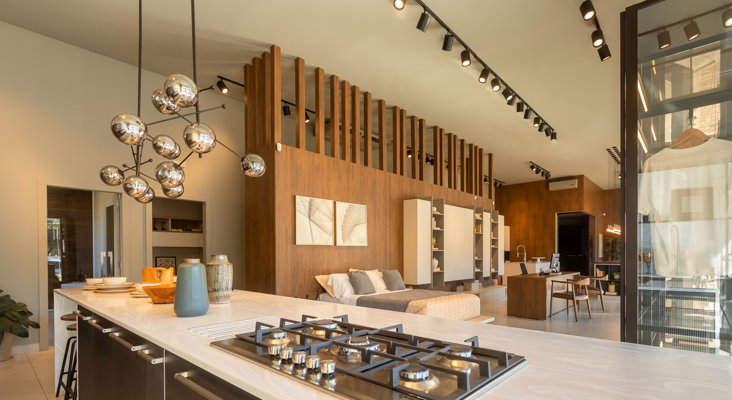 Showroom com ilha de cozinha, painéis ripados e marcenaria escura